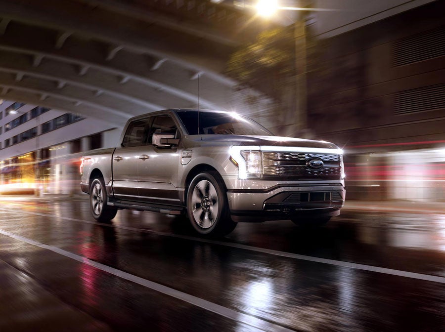 An F-150 Lightning® being driven in the city at night